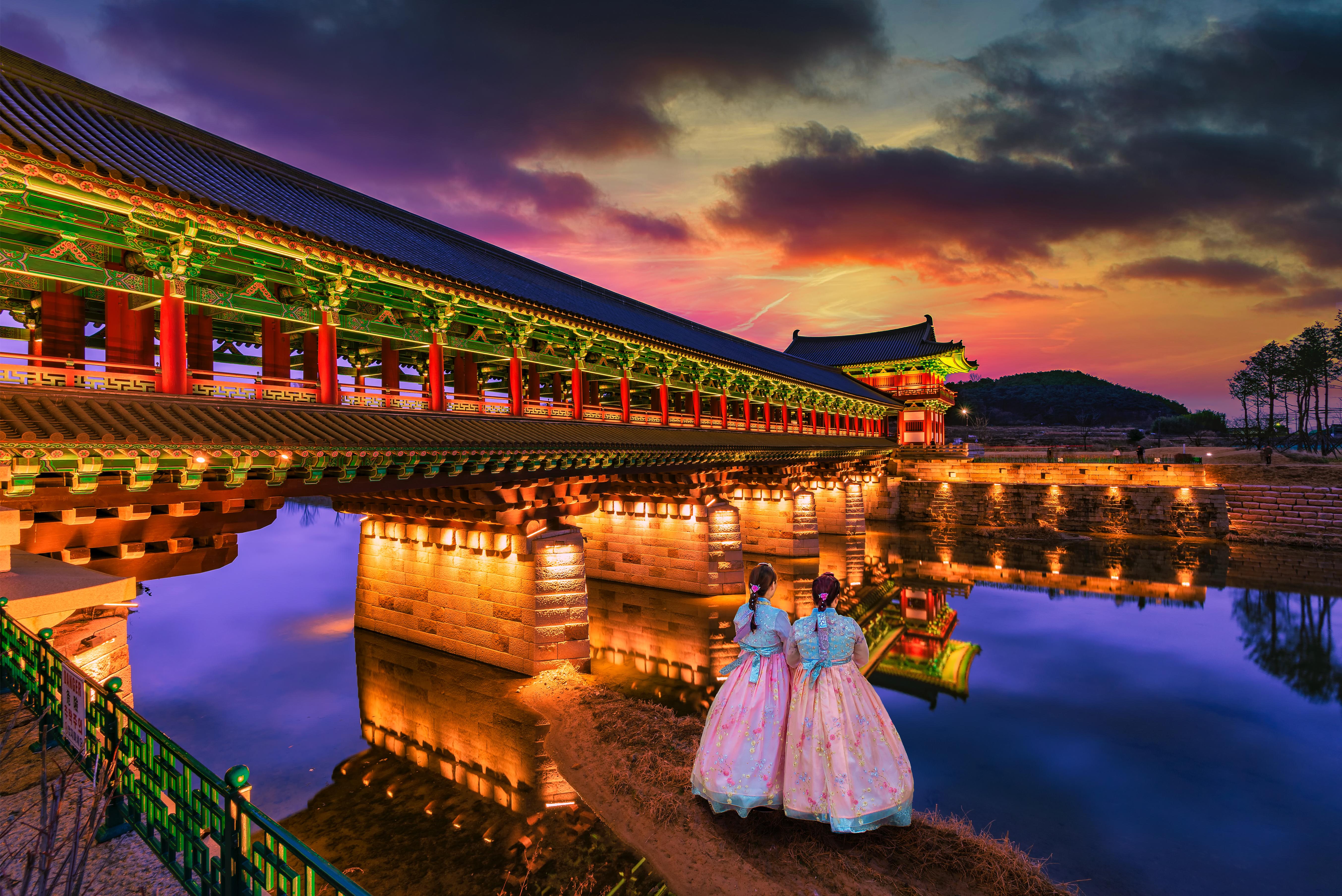Experience the serene glow of sunset reflecting off the water near Woljeonggyo Bridge where tradition and history come alive amidst ancient architecture and picturesque surroundings.
